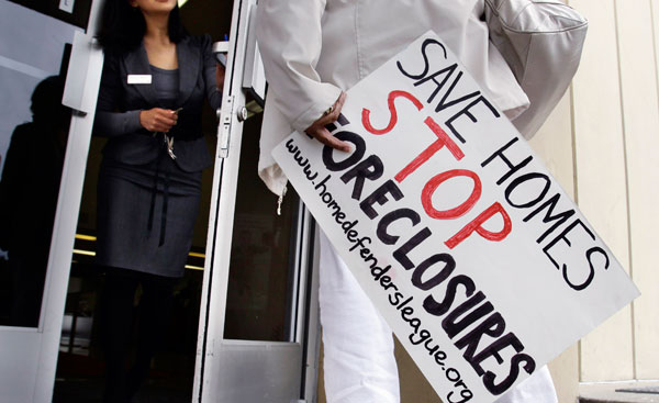 A member of the Home Defenders League talks with a Bank of America worker during a rally in front of a Bank of America branch in June 2011. Massive household debt is the reason why foreclosures have remained high in the past few years. (AP/Paul Sakuma)