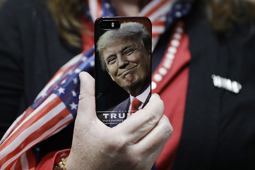 A woman holds up her cell phone before a rally with then-presidential candidate Donald Trump in Bedford, New Hampshire, September 29, 2016. ((AP/John Locher))