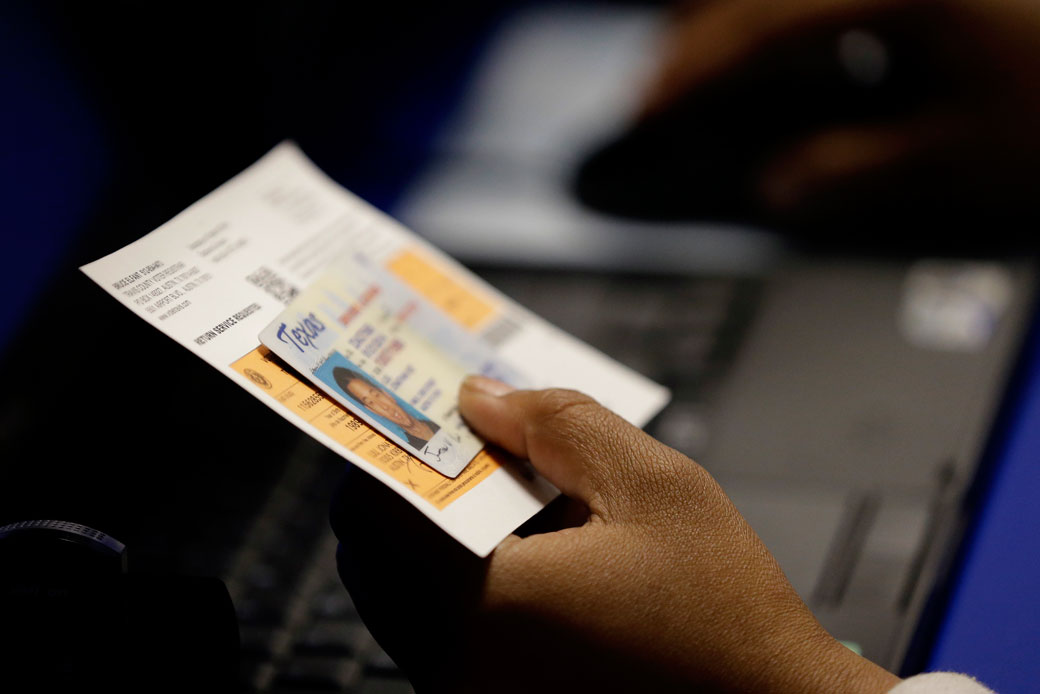 An election official checks a voter's photo identification at an early voting polling site in Austin, Texas, February 2014. (AP/Eric Gay)