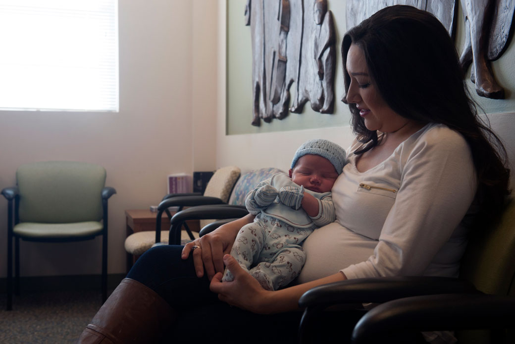 A mother sits with her 3-week-old son in the waiting room of a health center that offers health services to uninsured and underserved people in Denver, March 2017. (Getty/Jason Connolly/AFP)
