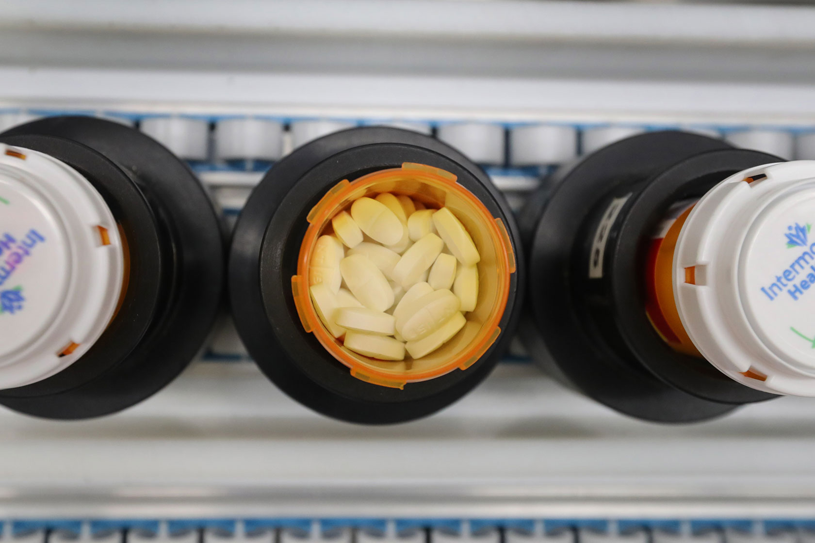 Bottles of prescription drugs are filled as they move down an automated line at a pharmacy