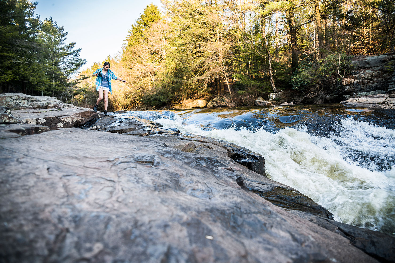 Girl walking on rocks next to water
