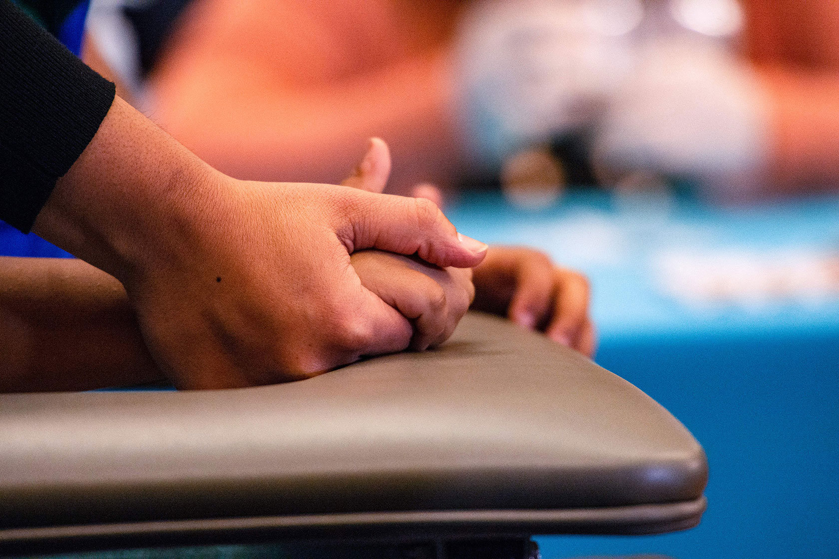 Photo shows a closeup view of an adult holding a child's hand