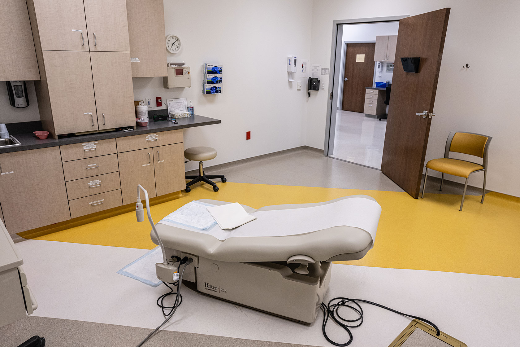 Photo shows an empty room with cabinets and an exam chair in the center